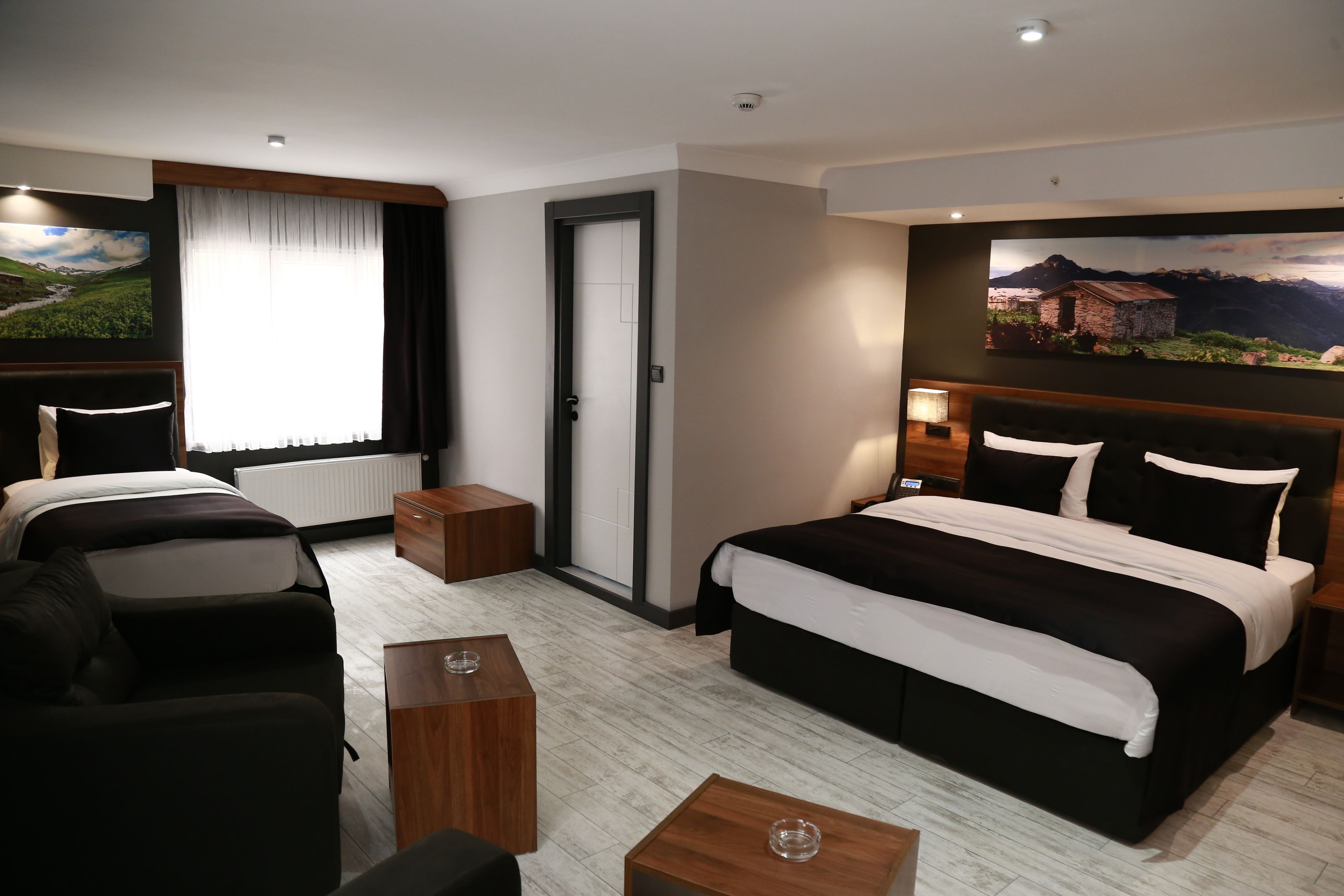 A hotel room with two beds, a sofa, a wooden coffee table, and a painting on the wall.