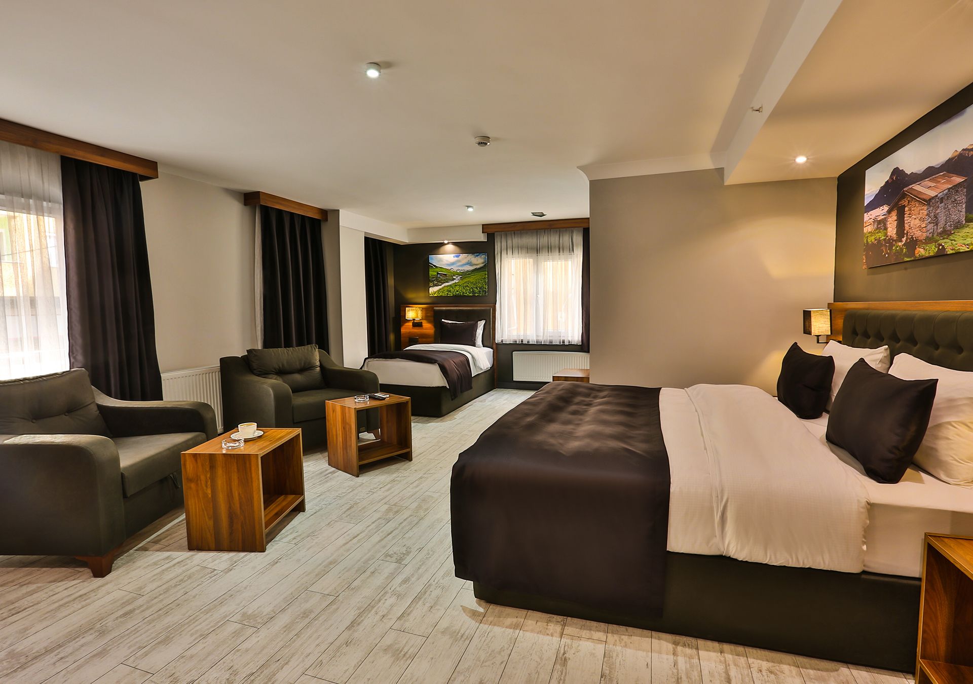 A hotel room with a large bed, two sofas, a coffee table, and a painting on the wall.