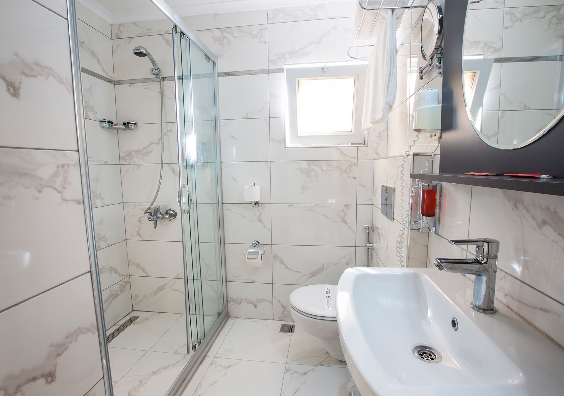 A modern bathroom with a glass-enclosed shower, a white sink, and a toilet.