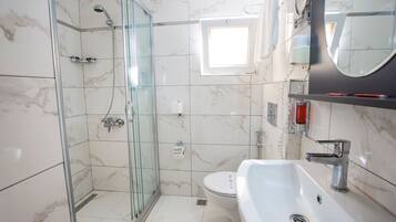 Un baño moderno con ducha envuelta en vidrio, un lavabo blanco y un inodoro.