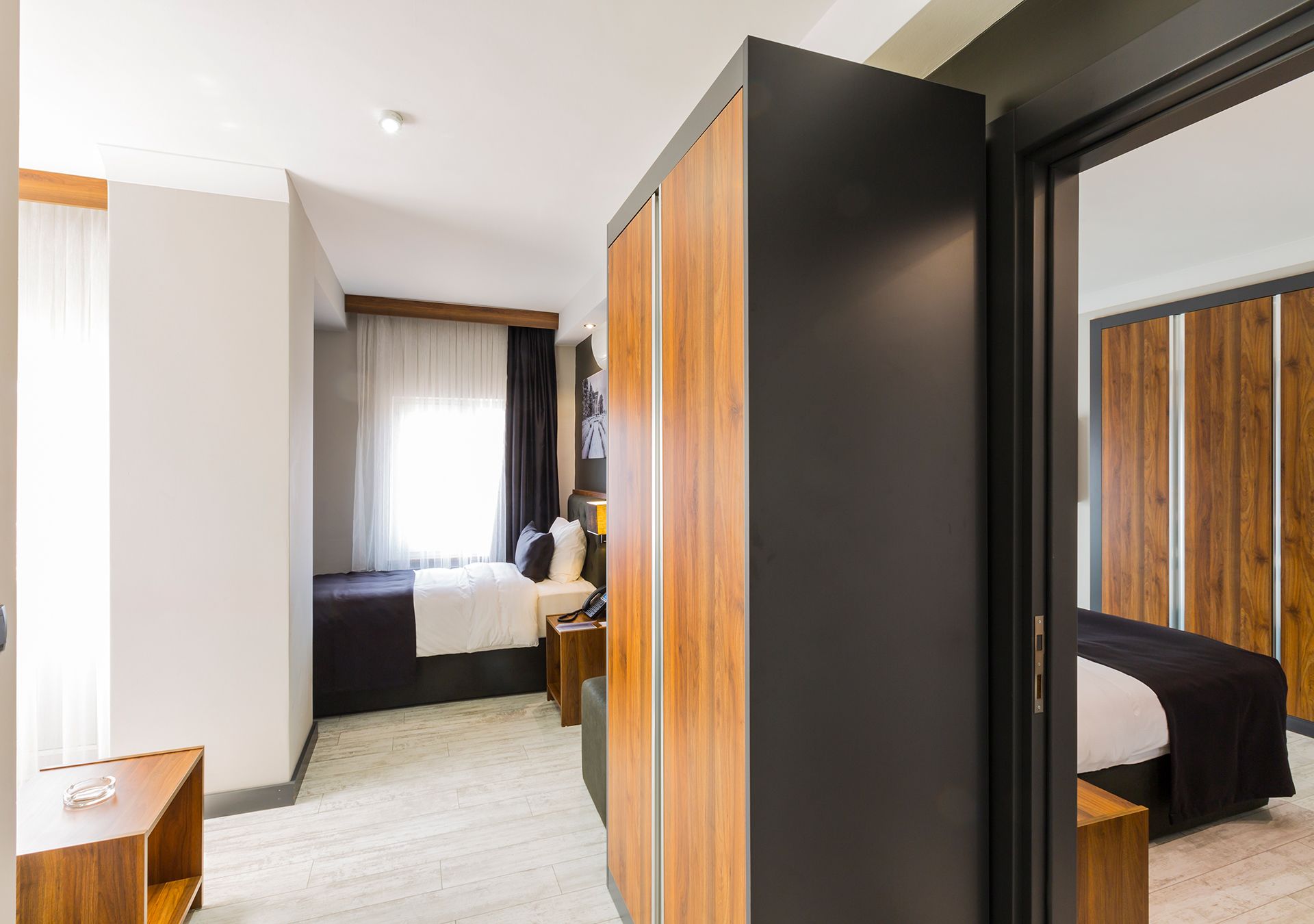 Una camera d'albergo moderna con un letto, un comodino e un armadio.