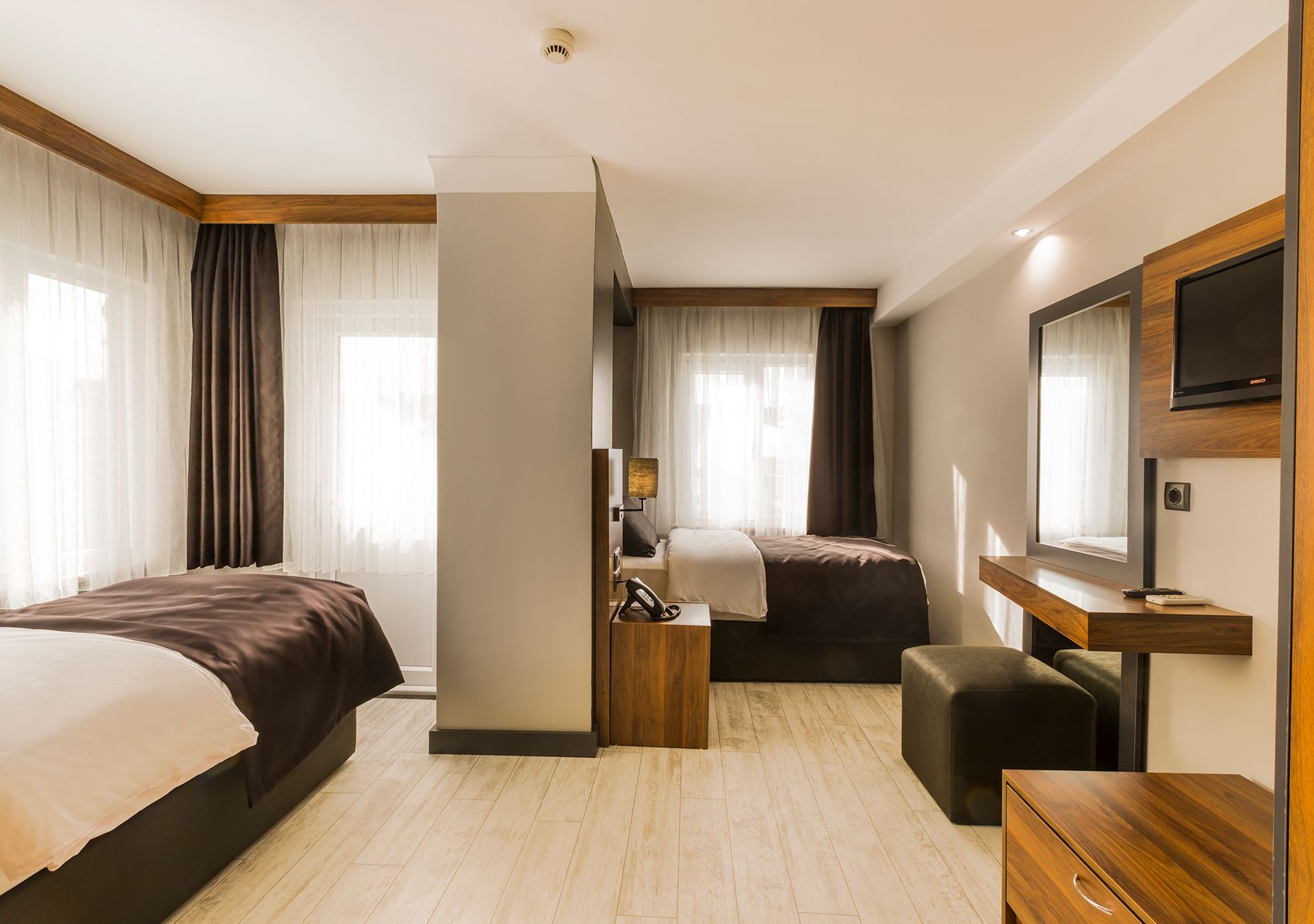 Een hotelkamer met twee bedden, een bureau, een televisie en een badkamer.