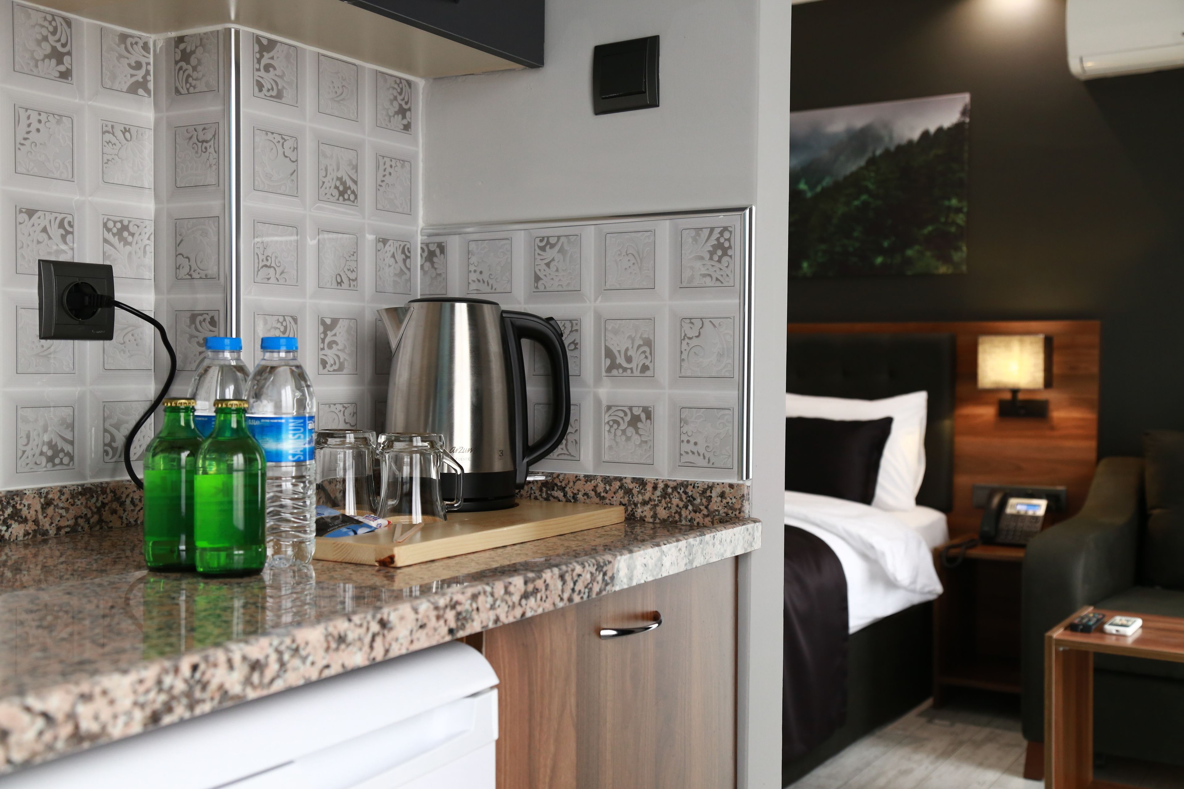 A kitchenette with a granite countertop, a kettle, two bottles of water, and a coffee maker.