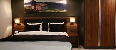 Un dormitorio moderno con una cama grande, cabecera de madera, dos mesitas de noche con lámparas y un armario.