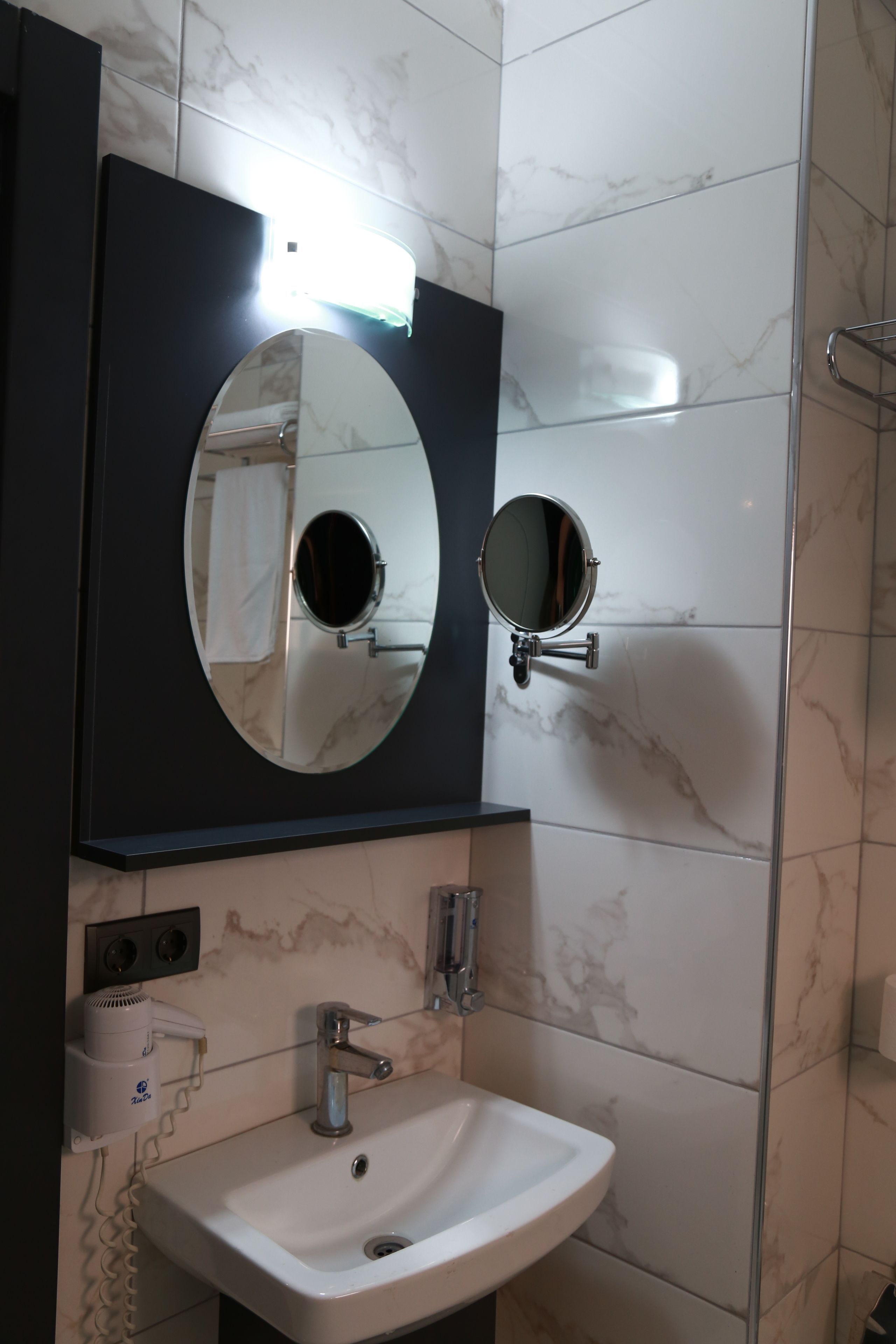 Une salle de bain avec un lavabo blanc, un miroir et un porte-serviettes.