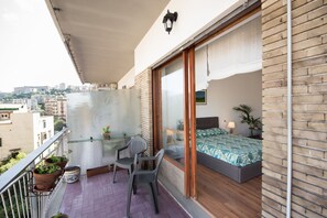 Ein Balkon mit einem Bett, einem Stuhl und Topfpflanzen.