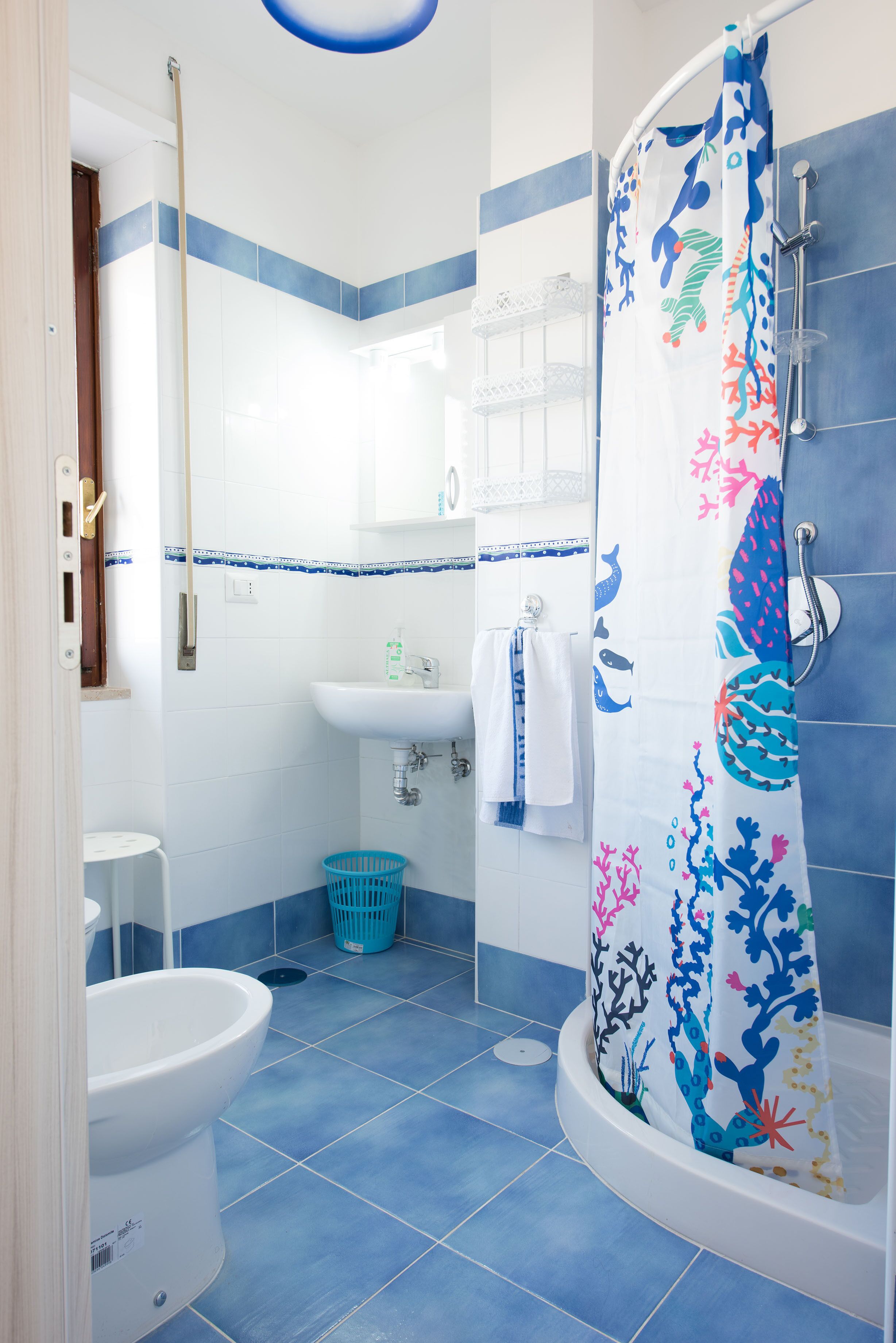 A bathroom with a shower, toilet, sink, and a blue tiled floor.