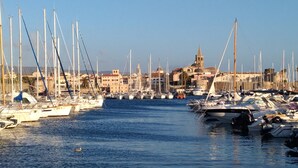 A marina with numerous sailboats docked, a prominent church with a bell tower, and a clear blue sky. - PENTHOUSE MARIS ALGHERO VIALE SARDINIA 104 LUXURY PENTHOUSE NEAR THE BEACH (Alghero)