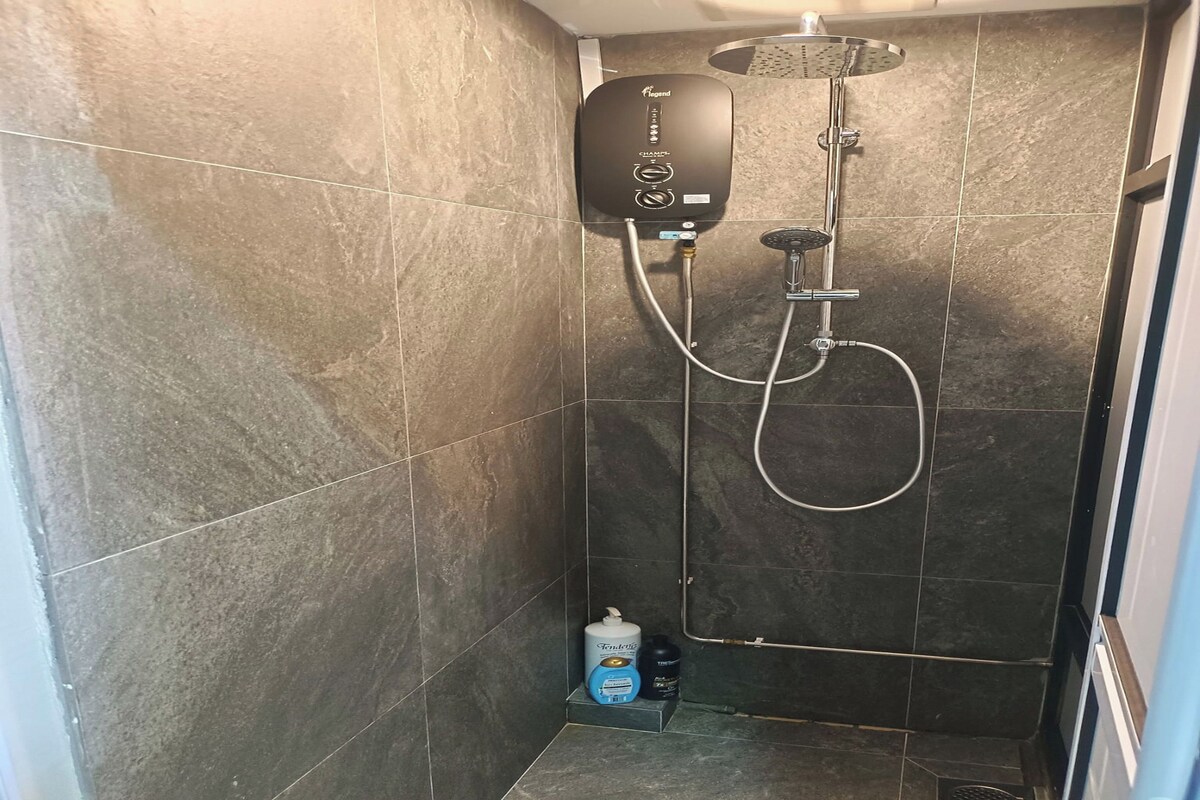 A shower with a control panel, a handheld showerhead, and a handheld shower attachment.