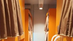 A corridor with bunk beds, each with a white ladder and brown curtains. - Century Service World - Hostel (Singapore)