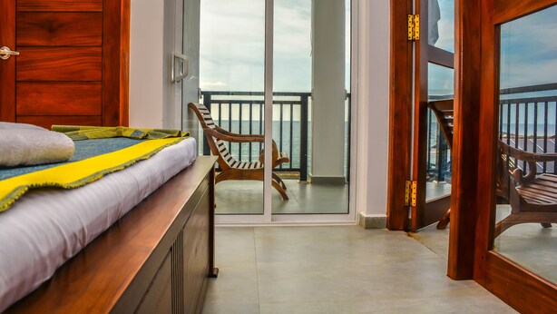 A room with a bed, a bench, and a view of the balcony. - Rominrich (Hikkaduwa)