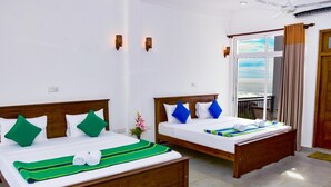 Two wooden beds with white linens and green and blue pillows, a green striped blanket, and a small vase of flowers. - Rominrich (Hikkaduwa)