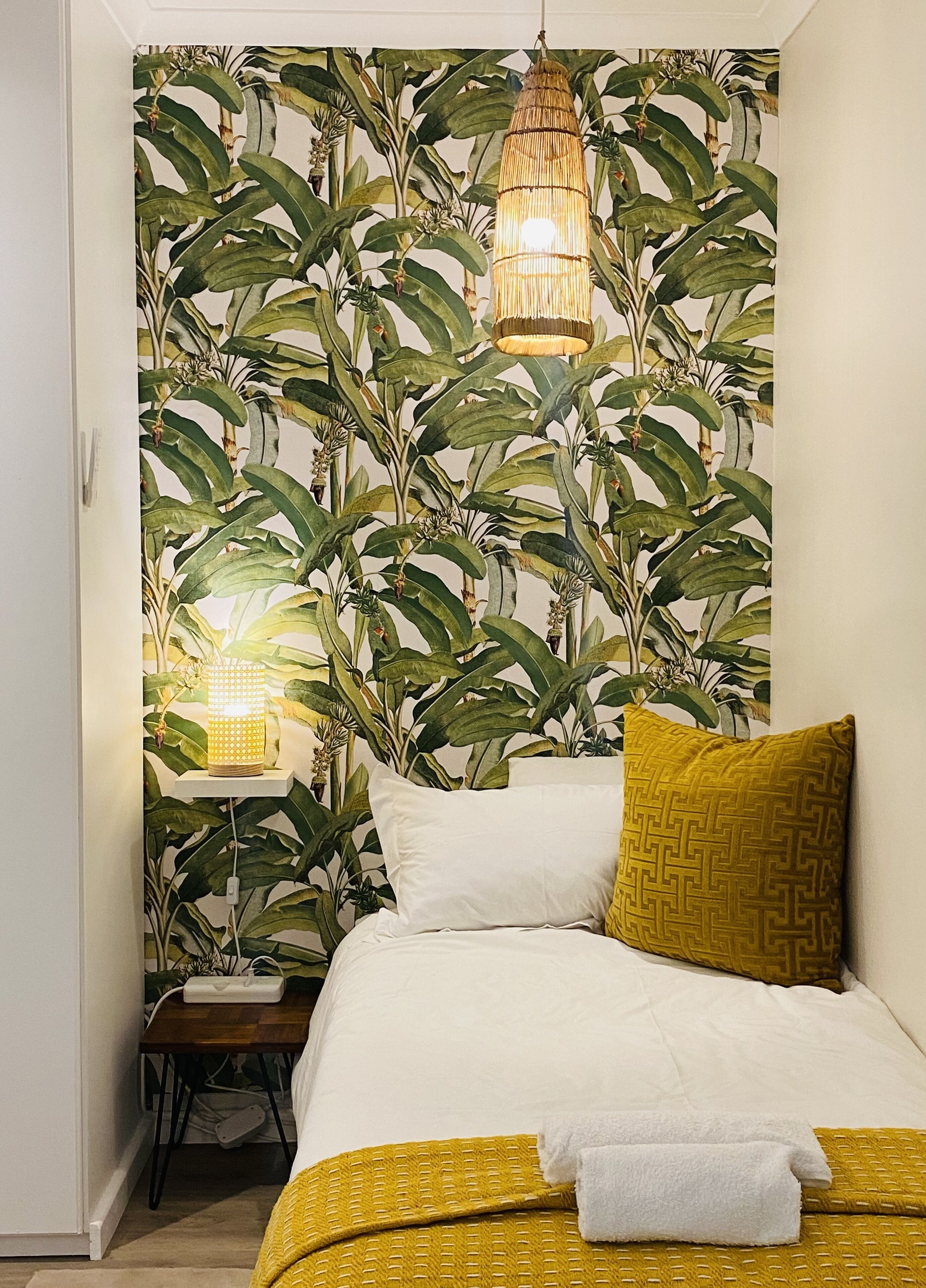 A bedroom with a bed, pillows, and a nightstand with a lamp.