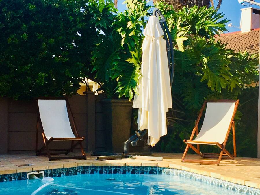 Una piscina con dos tumbonas y una sombrilla.