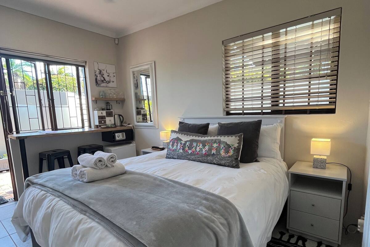 A bedroom with a bed, bedside table, lamp, and a ceiling fan.