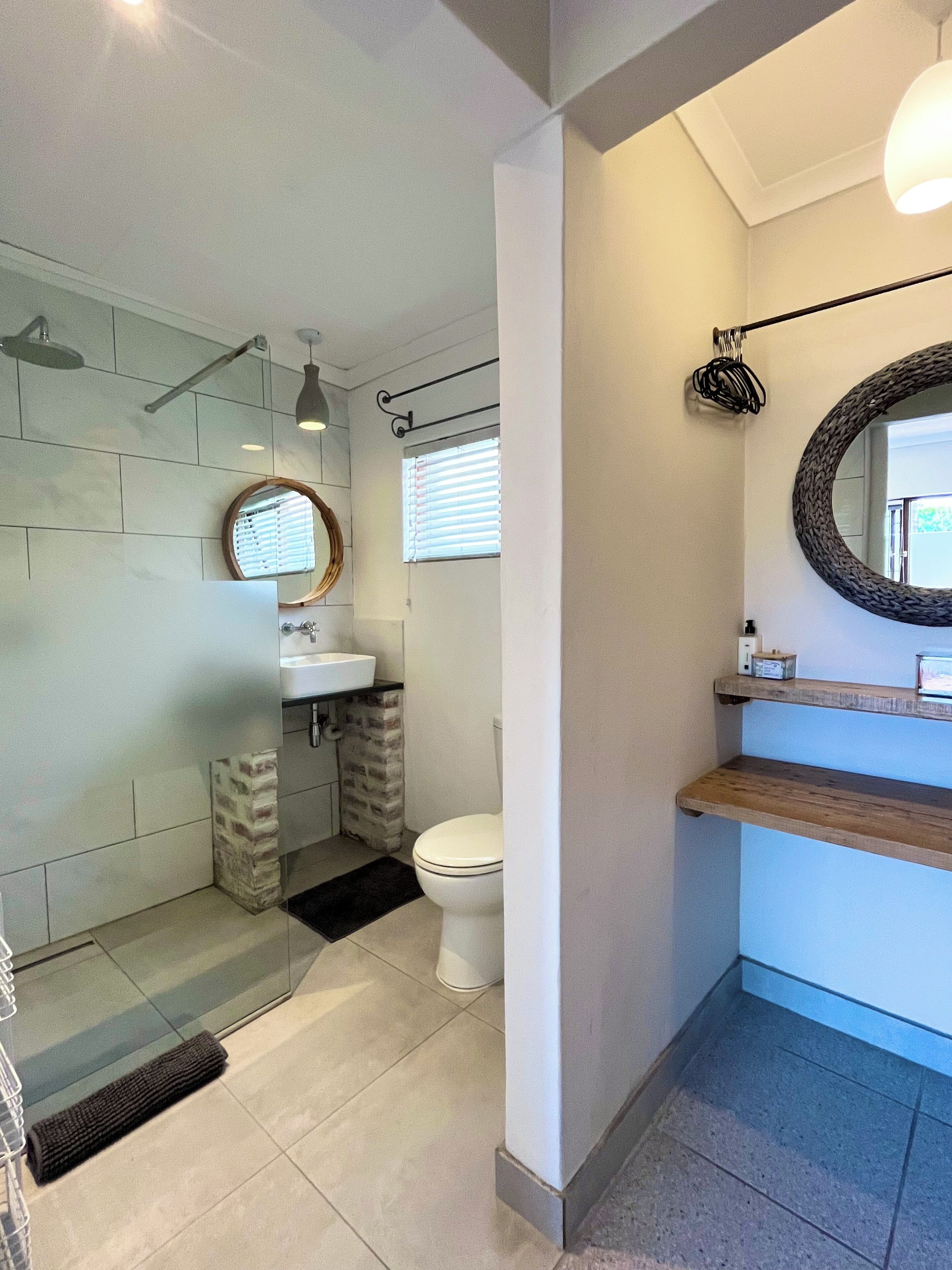A modern bathroom with a glass shower enclosure, a white toilet, and a wooden vanity with a mirror.