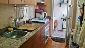 A kitchen with wooden cabinets, a granite countertop, a sink, and a microwave. - Family Apartment Just Steps from the Sea in Palamós 🏖️☀️ (Palamós)