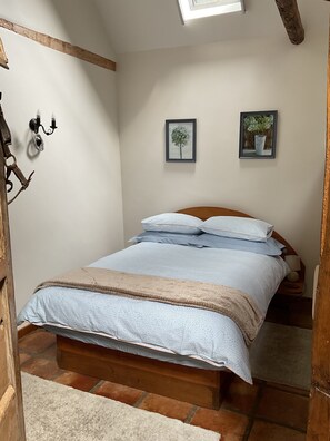 Une chambre avec un lit en bois, un puits de lumière et deux tableaux encadrés accrochés au mur.