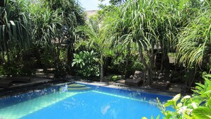 A rectangular swimming pool surrounded by lush greenery and trees. - Gili Hideaway (Gili Trawangan)