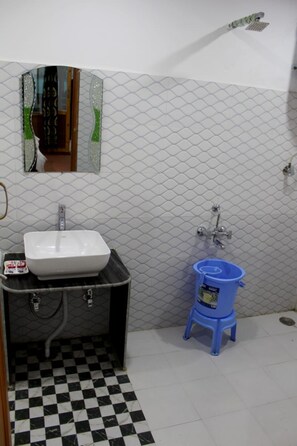 A bathroom with a white sink, a mirror, a shower, and a blue stool. - The Ladakh Resort (Kargil)