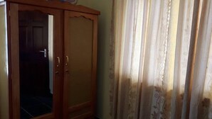 Ein Zimmer mit einem Holzschrank, einer Tür und einem Vorhang.