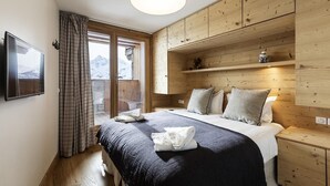 Un dormitorio con cama, cabecera de madera, estanterías empotradas y ventana con vista a montañas.