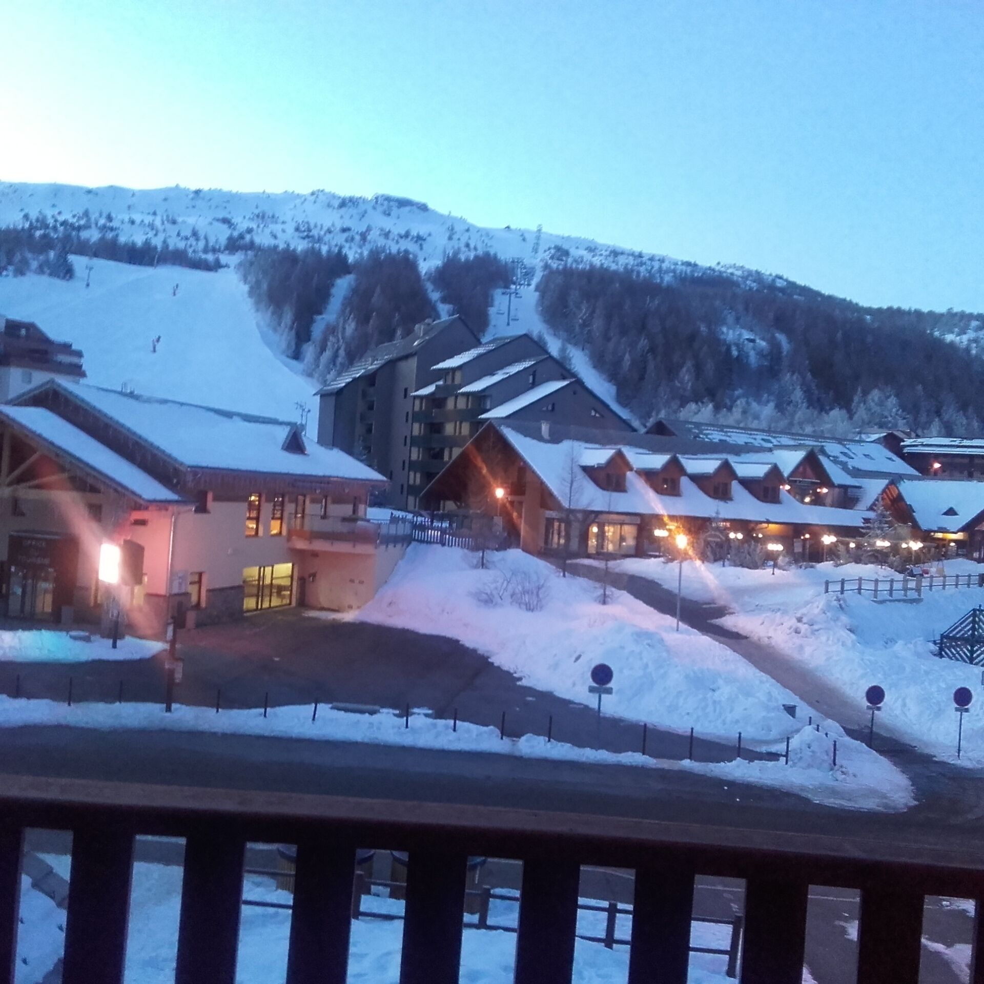 Een met sneeuw bedekt wintersportresort met meerdere gebouwen, waaronder een lodge en een skilift.