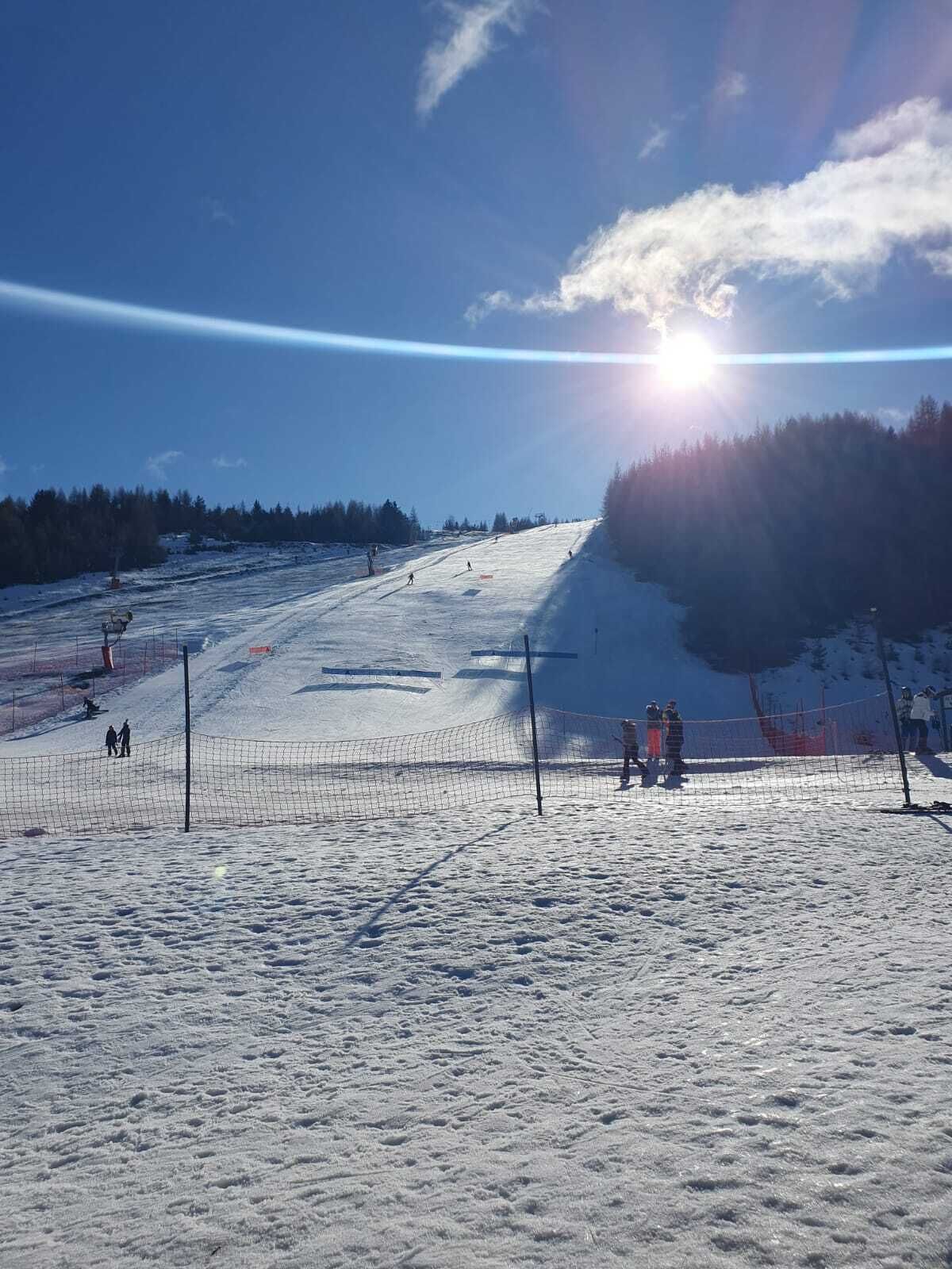 A snowy ski slope with a clear sky and sun shining.