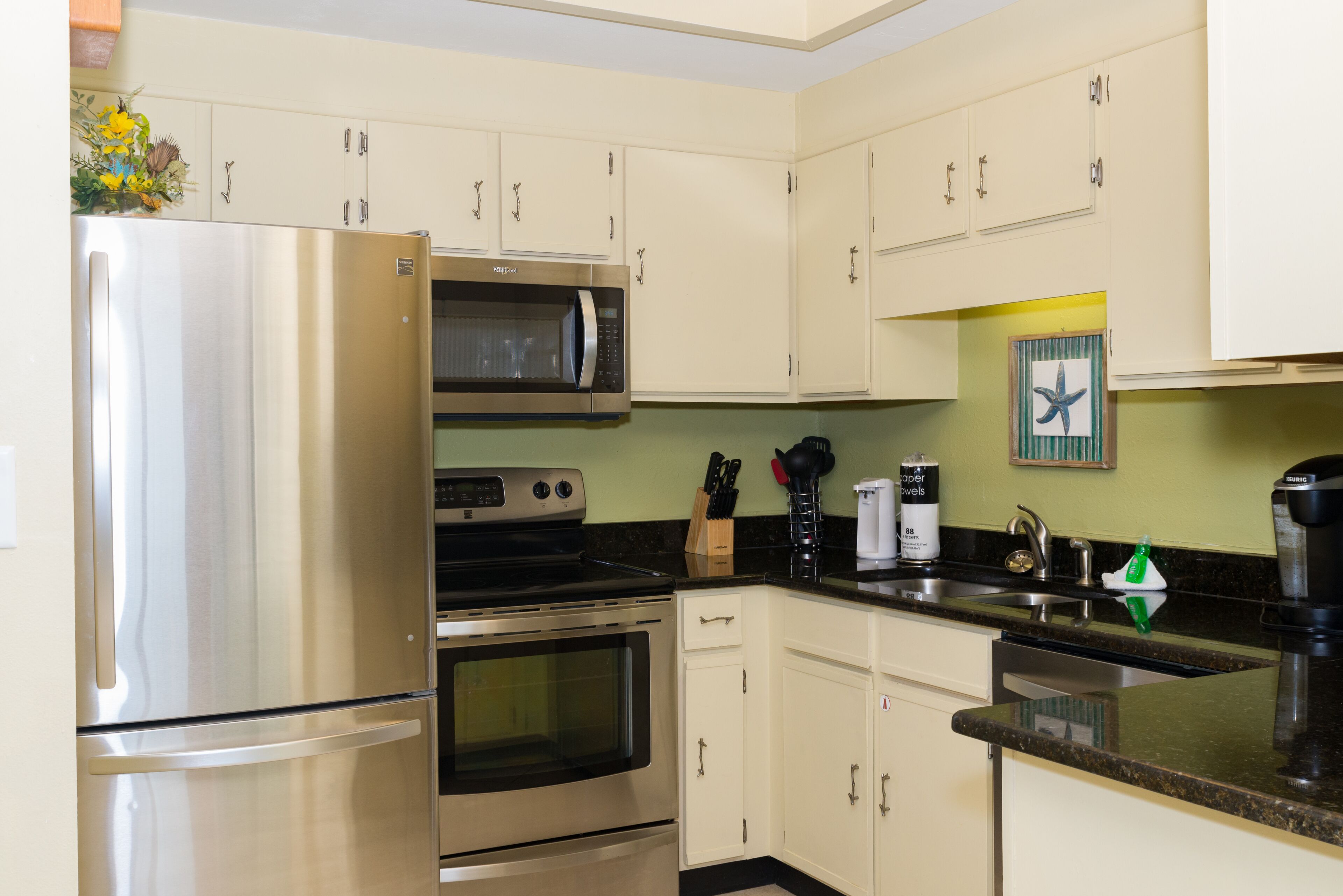 A kitchen with stainless steel appliances, including a refrigerator, microwave, oven, and dishwasher.
