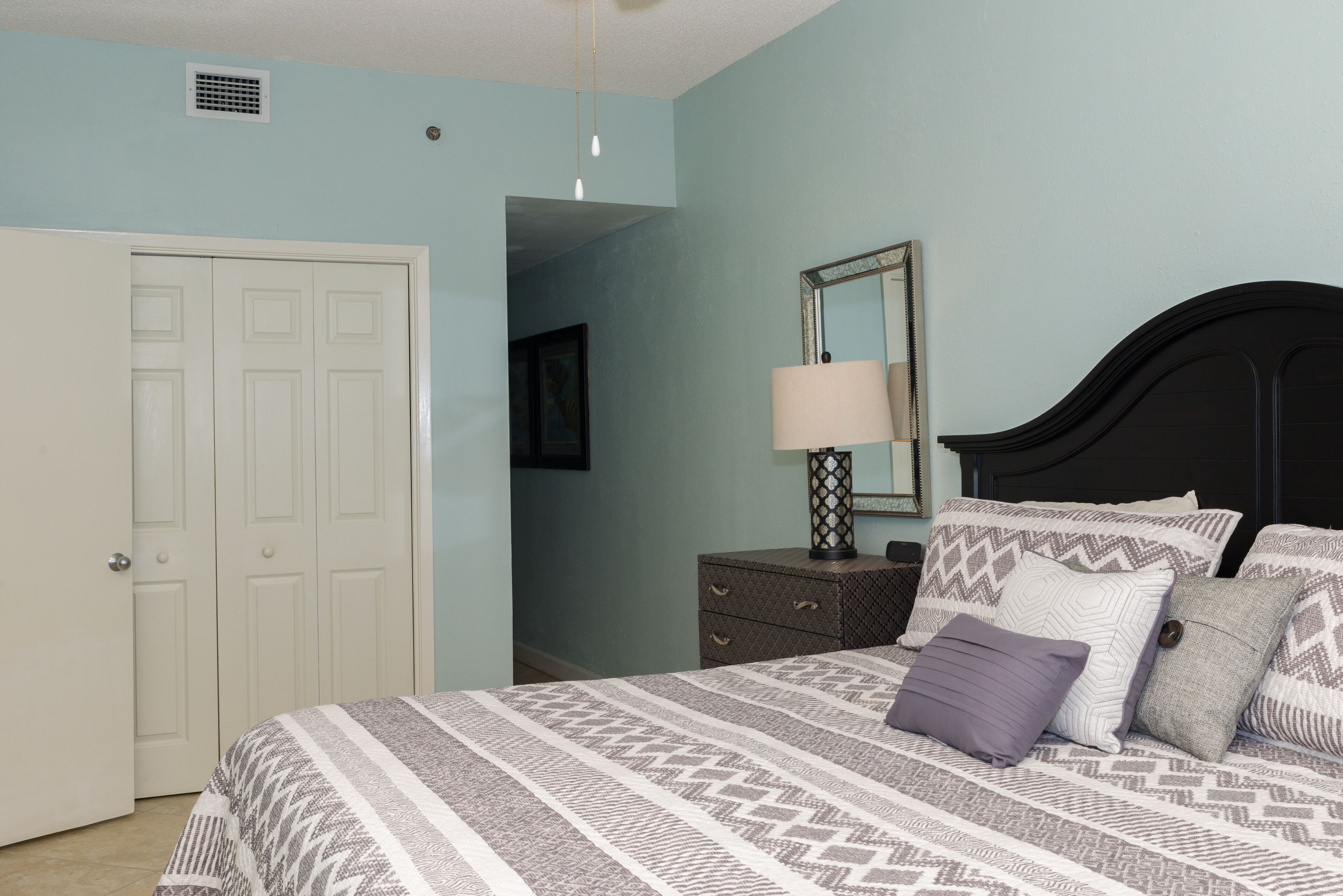 A bedroom with a bed, dresser, and a door.
