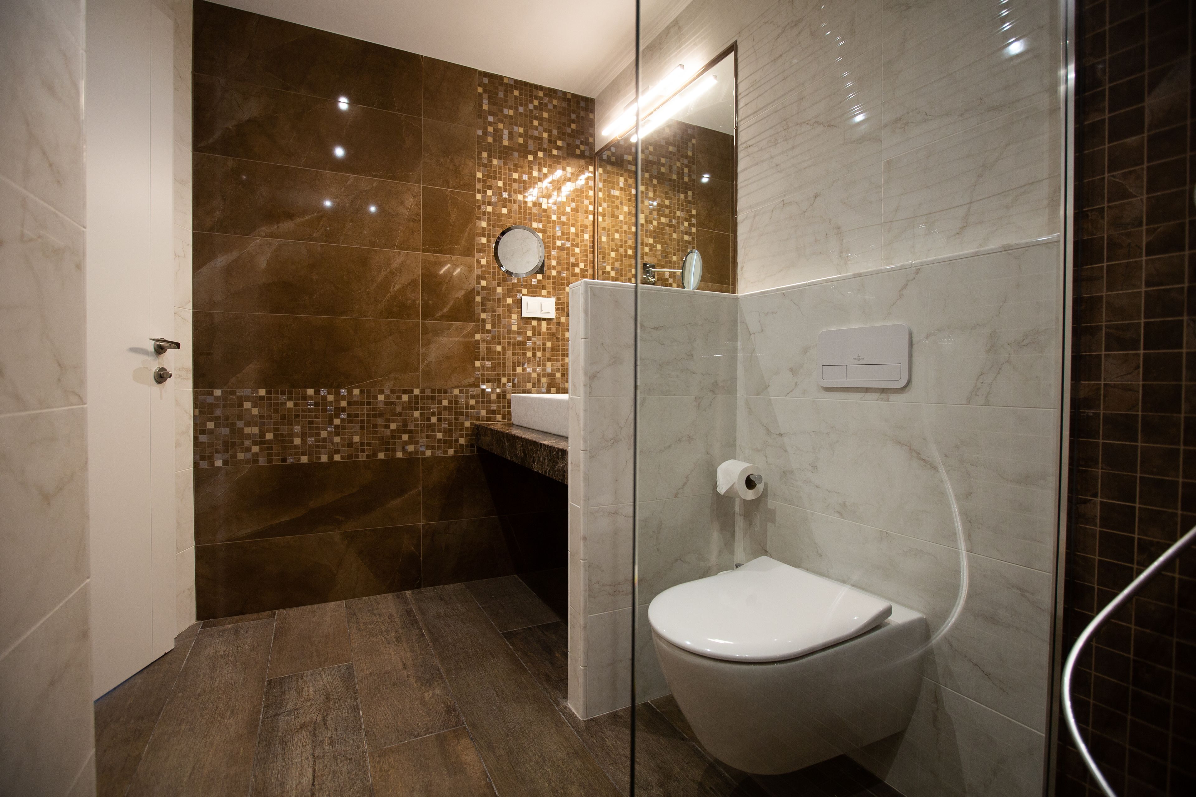 Een moderne badkamer met een douchecabine van glas, een toilet en een wastafel.
