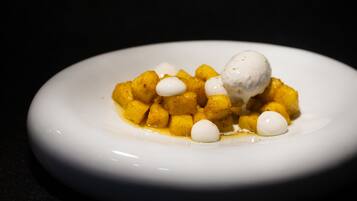 Plato blanco con un postre de cubos de comida amarilla y una porción de helado blanco.