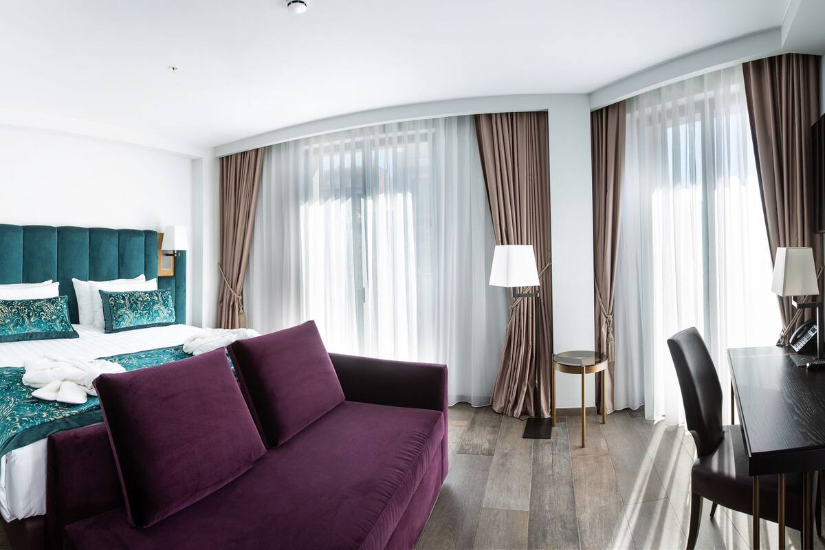 Una habitación de hotel con una cama, un sofá púrpura, un escritorio y una silla.