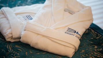 Two folded robes with a logo on them, placed on a patterned fabric.