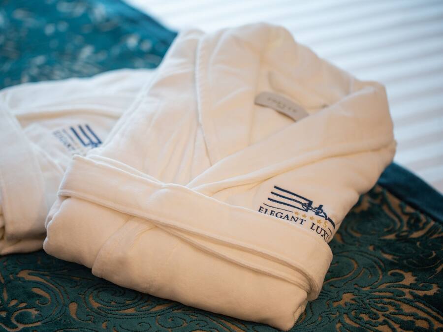 Two folded robes with a logo on them, placed on a patterned fabric.
