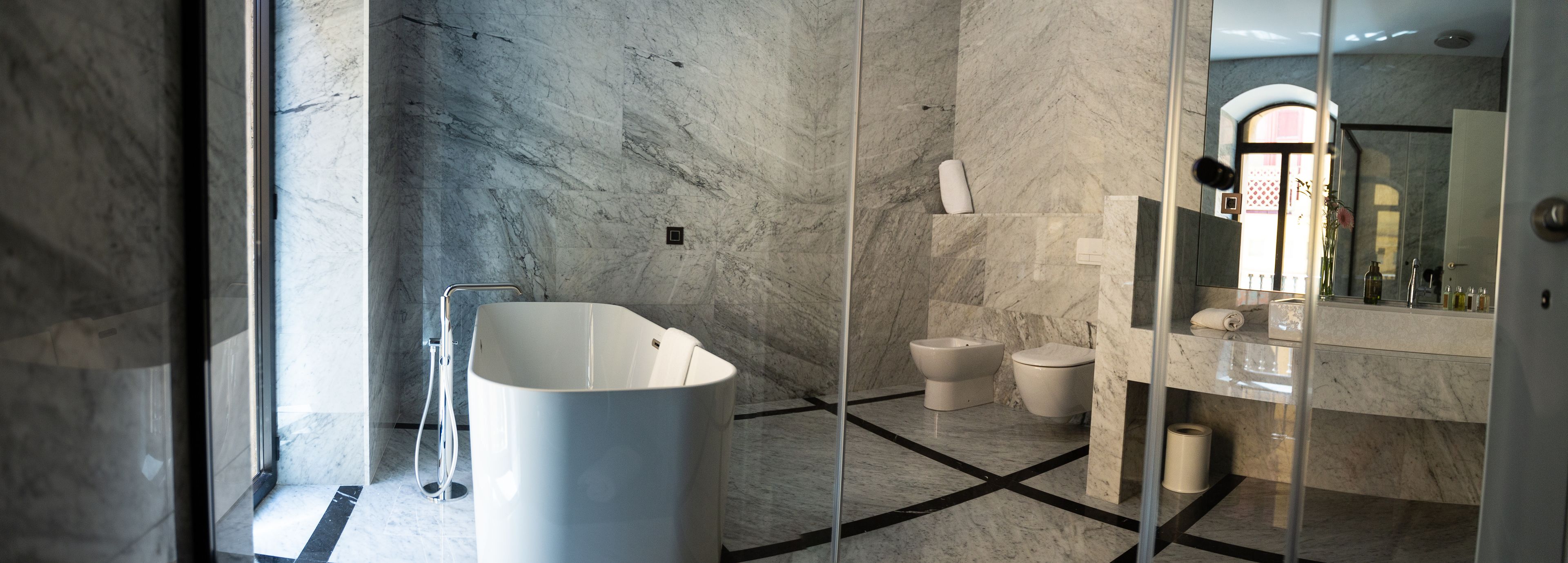 A modern bathroom with a freestanding bathtub, a separate toilet, and a glass-enclosed shower area.