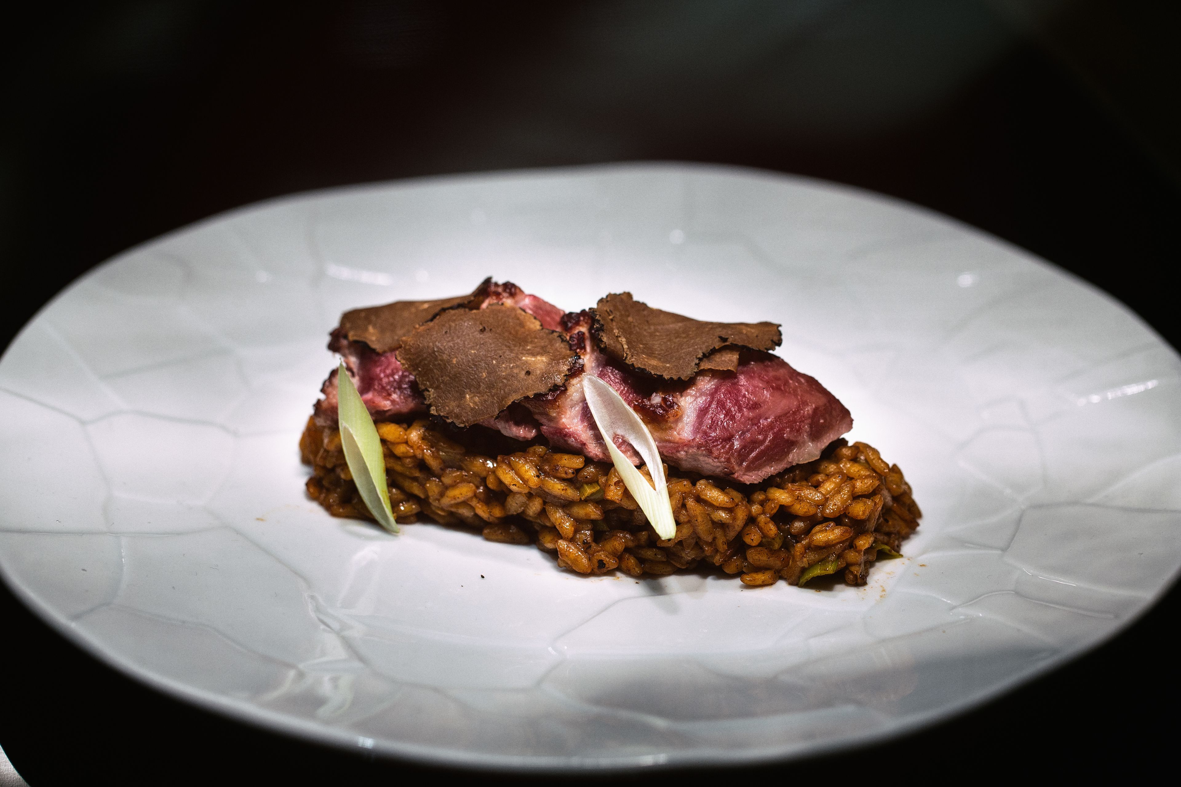 A plate with a dish consisting of rice and meat, possibly beef, with a garnish.