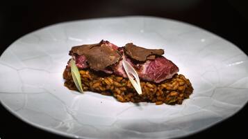 A plate with a dish consisting of rice and meat, possibly beef, with a garnish.