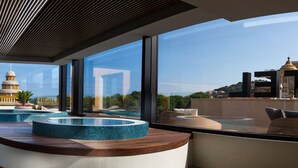 Un pasillo moderno de hotel con vistas a una torre histórica, una zona de piscina y un área de descanso con vista a la ciudad.