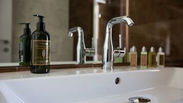 Un lavabo de salle de bain avec deux flacons de savon liquide pour les mains de la marque L'OCCITANE et un robinet chromé.