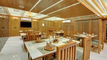 A dining area with wooden furniture, tables set with plates, and a chandelier.