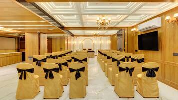 A conference room with rows of chairs, a podium, and a large screen.
