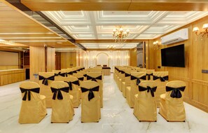 A conference room with rows of chairs, a podium, and a large screen. - Hotel Shital Inn (Ahmedabad)