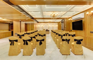 A conference room with rows of chairs, a podium, and a large screen.