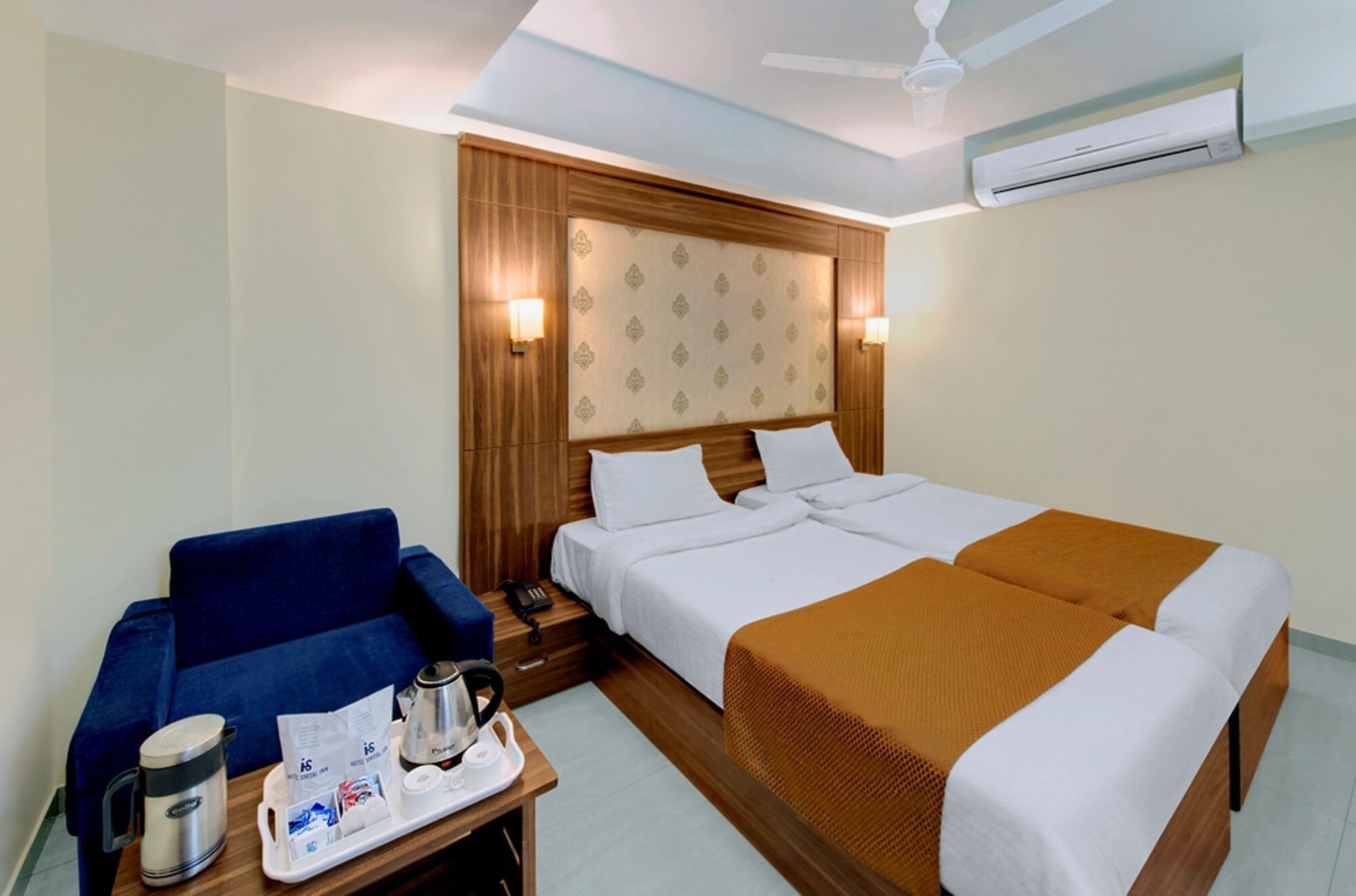 Hotelkamer met twee bedden, een bank, een salontafel met koffiezetapparaat en een airconditioning.