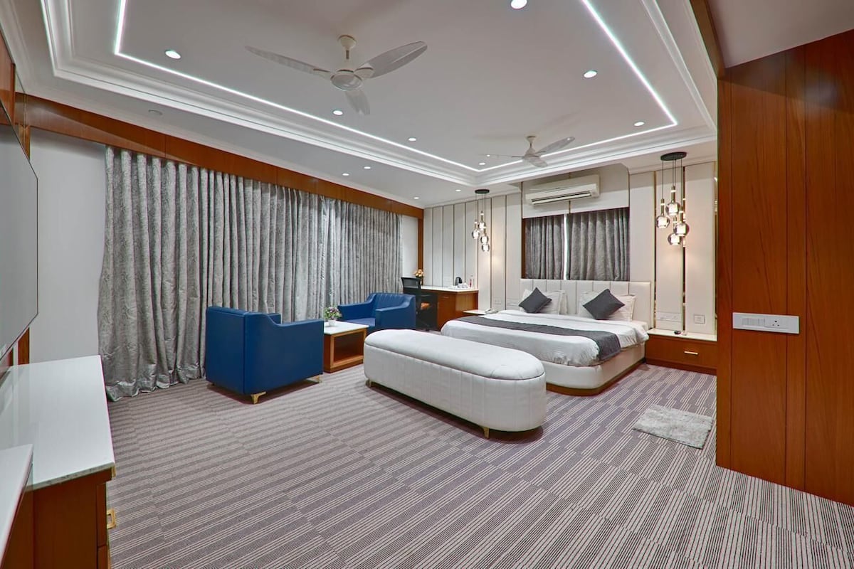 Une chambre d’hôtel moderne équipée d’un grand lit, de deux canapés, d’un bureau et d’un ventilateur de plafond.