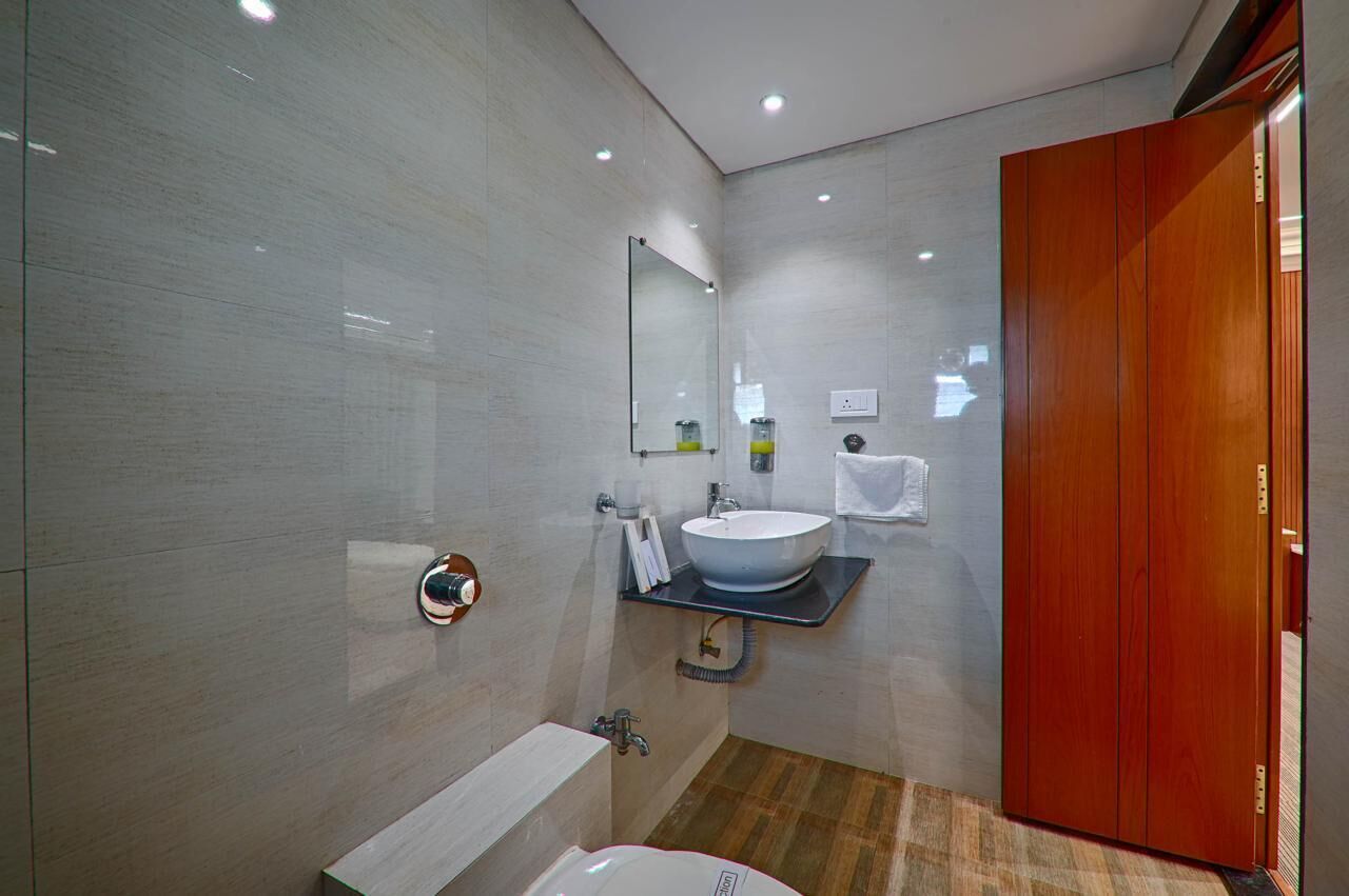 A modern bathroom with a large mirror, a sink, and a toilet.