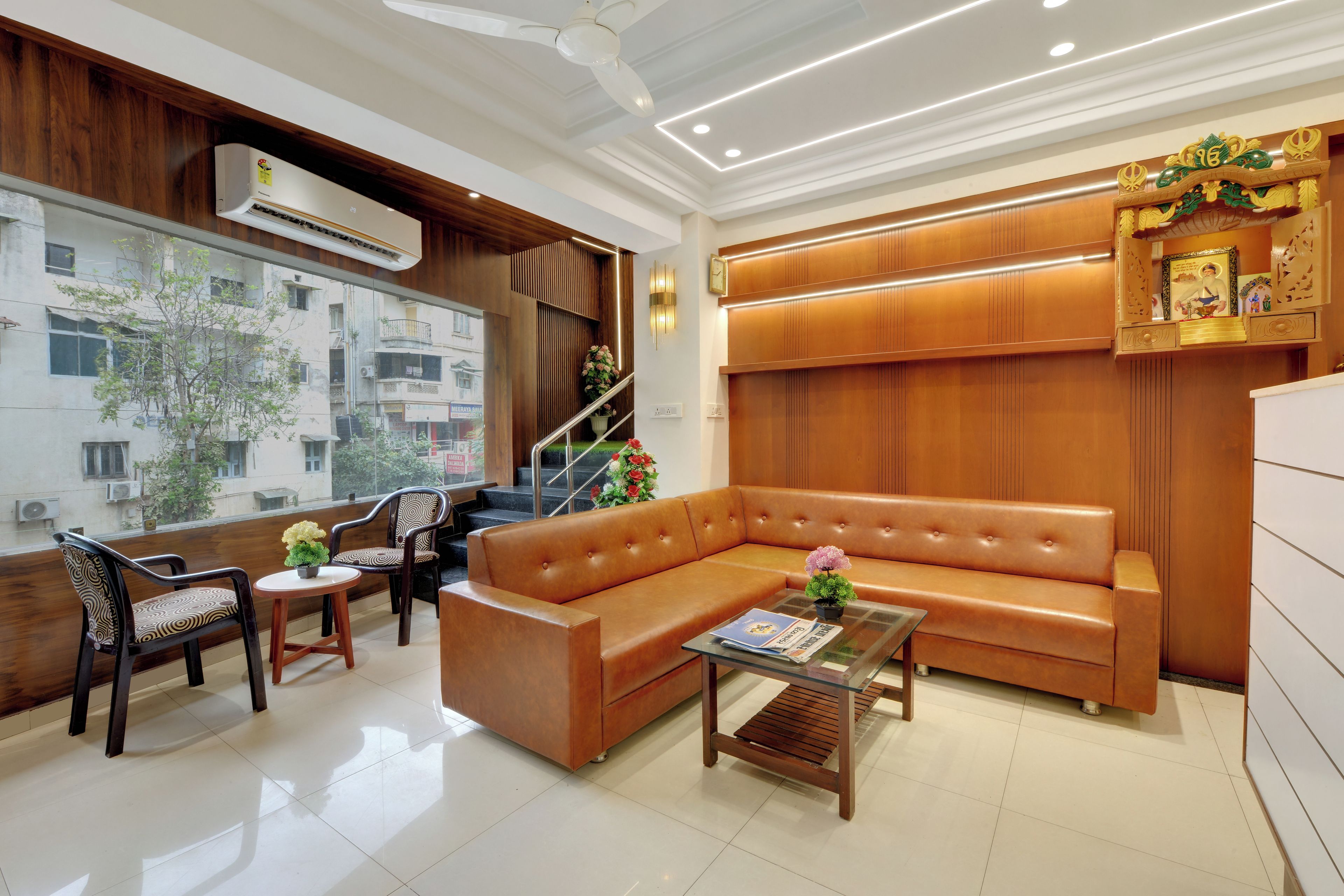 Una sala de estar moderna con un sofá de cuero, dos sillones, una mesa de centro y una escalera con detalles de madera.