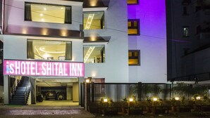 Entrada de um hotel com um letreiro de neon que diz "HOTEL SHITAL INN".