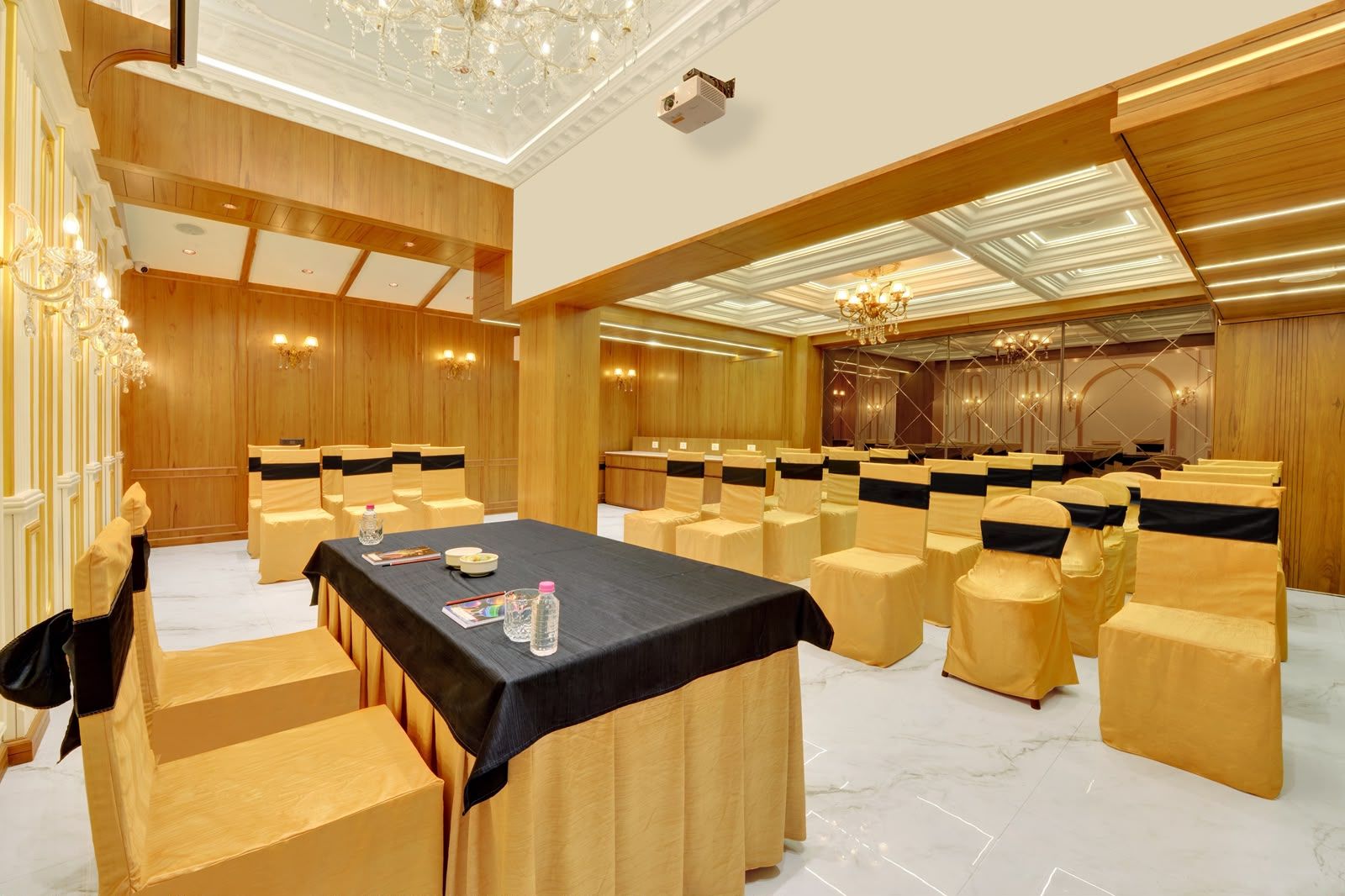 A conference room with rows of chairs, a table with a black tablecloth, and chandeliers.